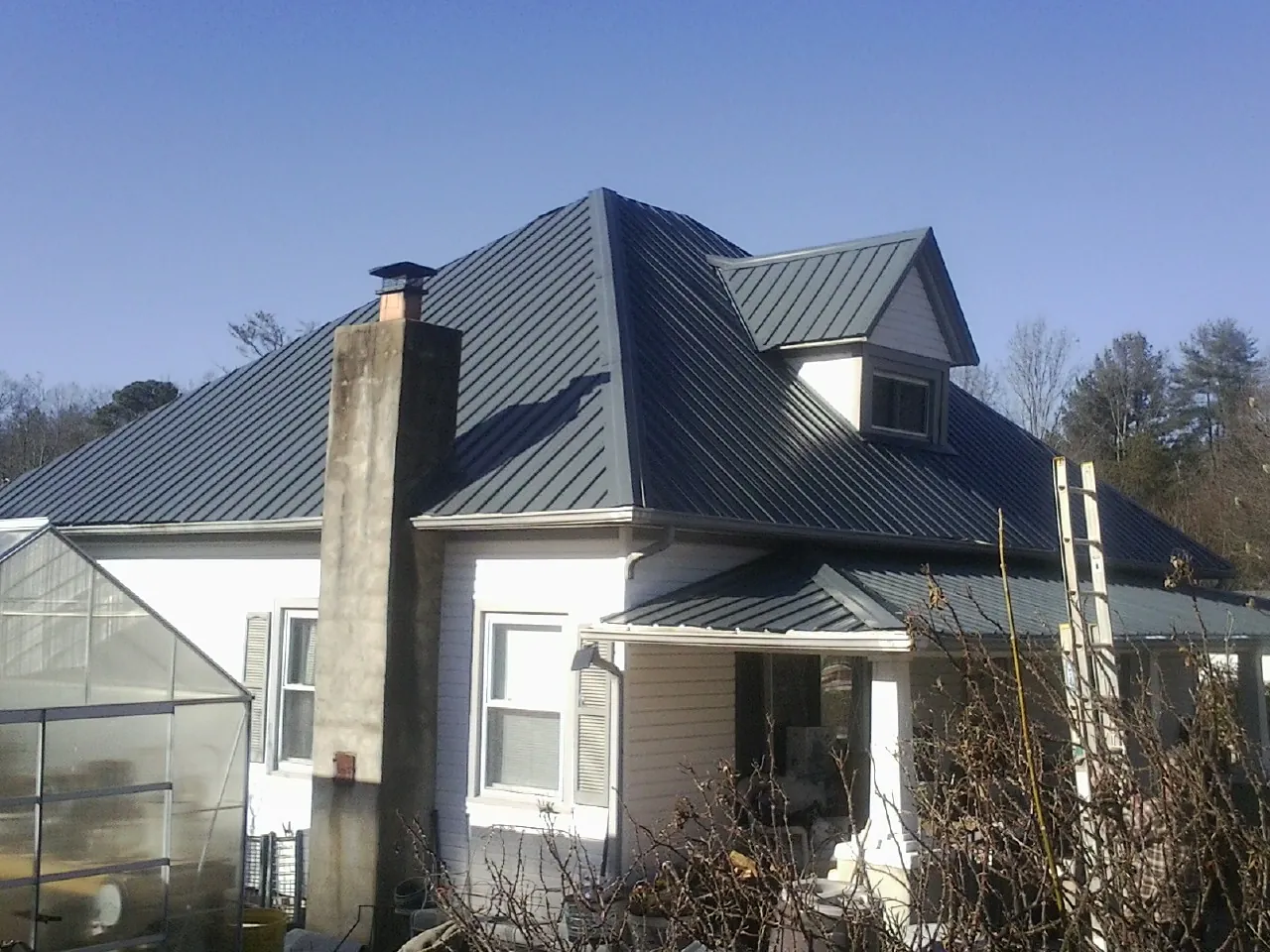 Dark blue standing seam metal roof on a white farmhouse with dormer — Slate & Tile Roof Repair by Roofing Brothers in New Zion