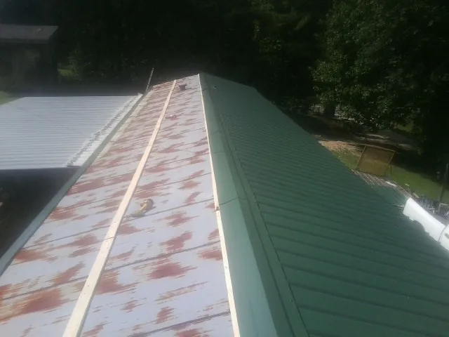Old rusted panels beside newly installed green metal roofing — Wind Damage Roof Repair by Roofing Brothers in New Zion