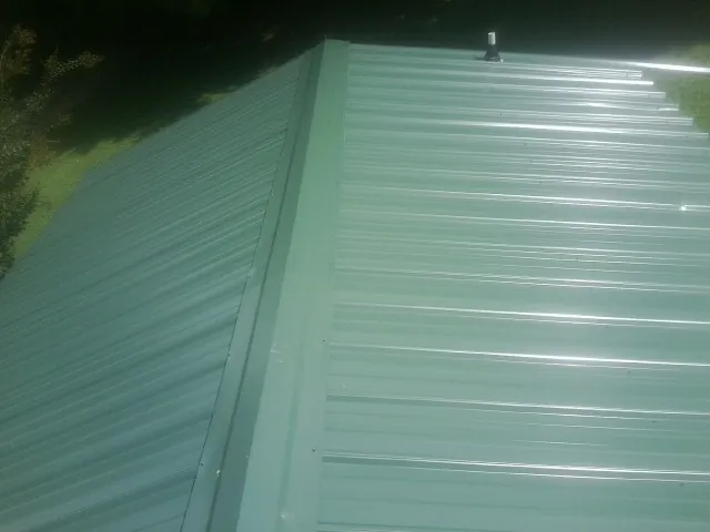 New green metal panels meeting at the ridge of a roof — Flat Roof Repair work by our crew in New Zion