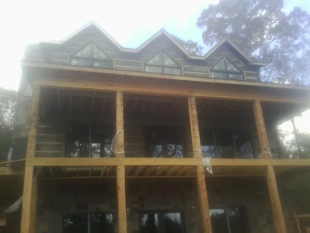 Dormers and porch framing on a large log home under construction — Roof Coating work by our crew in New Zion