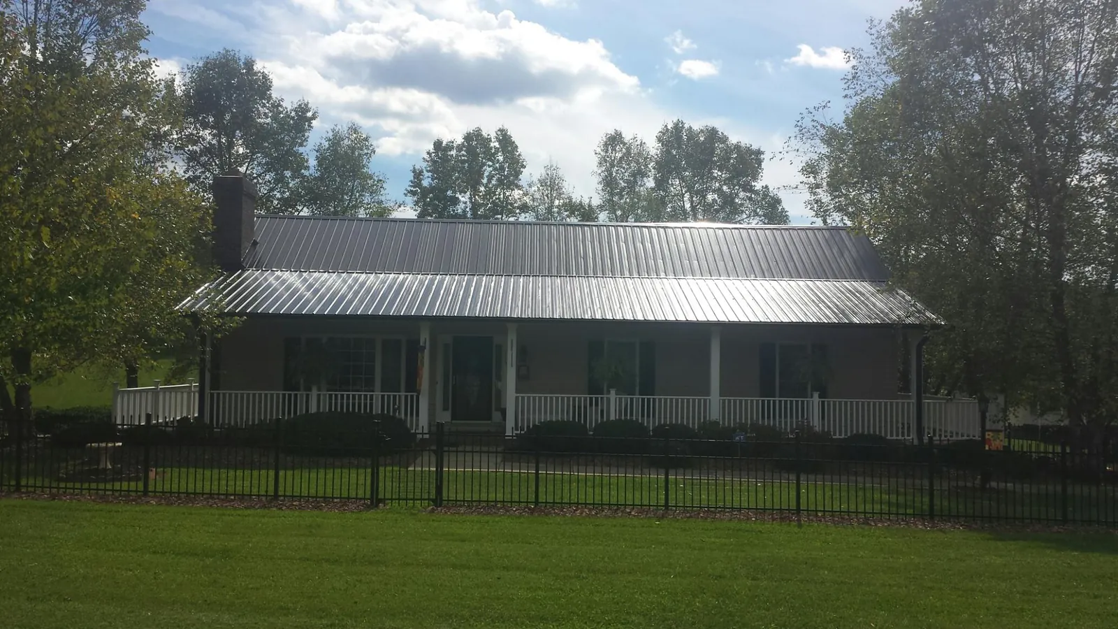 Gray metal roof on a brick ranch with a full width front porch — Gutter Guard Installation work by our crew in New Zion