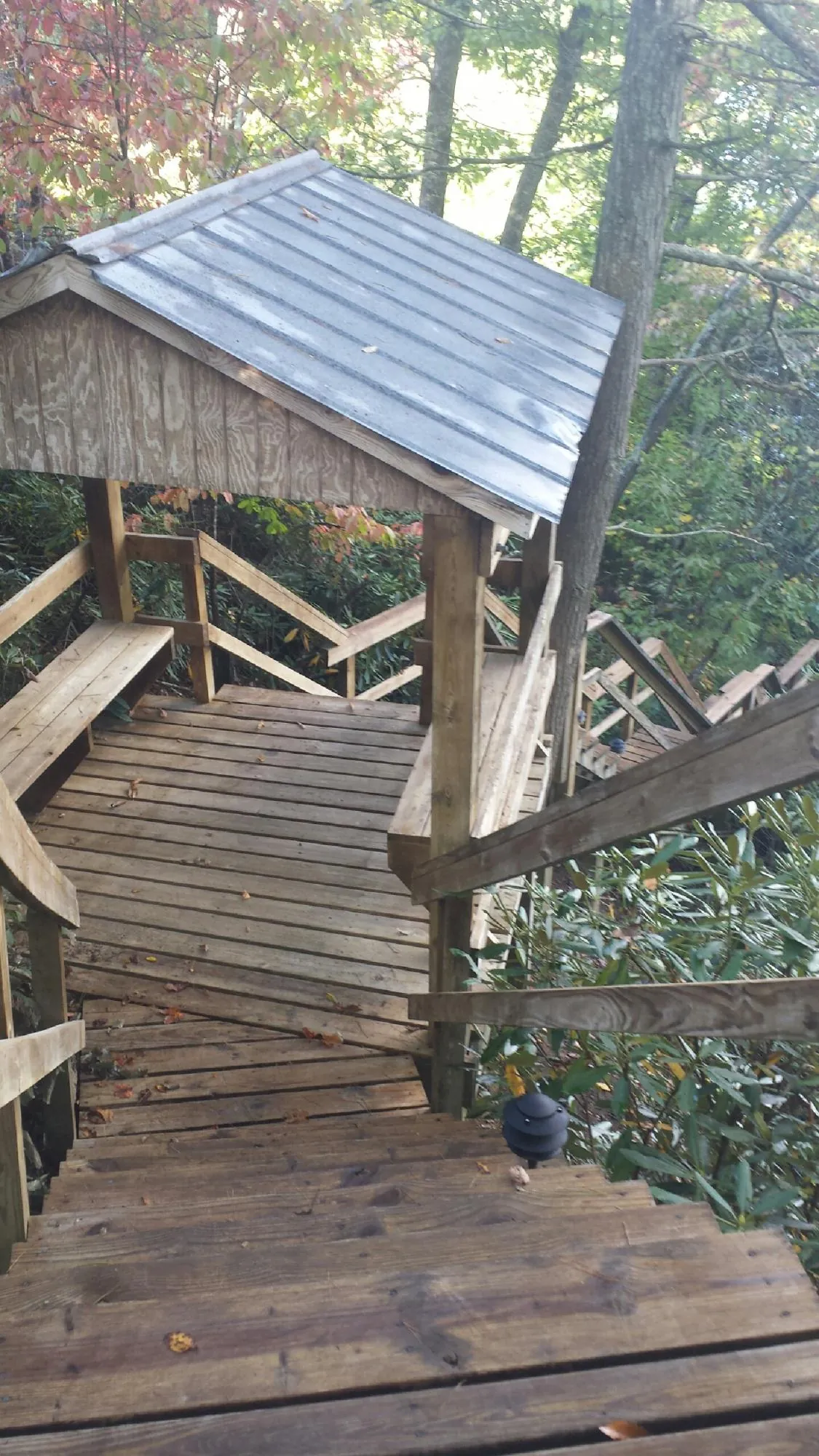 Metal roofed shelter over wooden steps on a wooded walkway — Skylight Repair & Installation work by our crew in New Zion