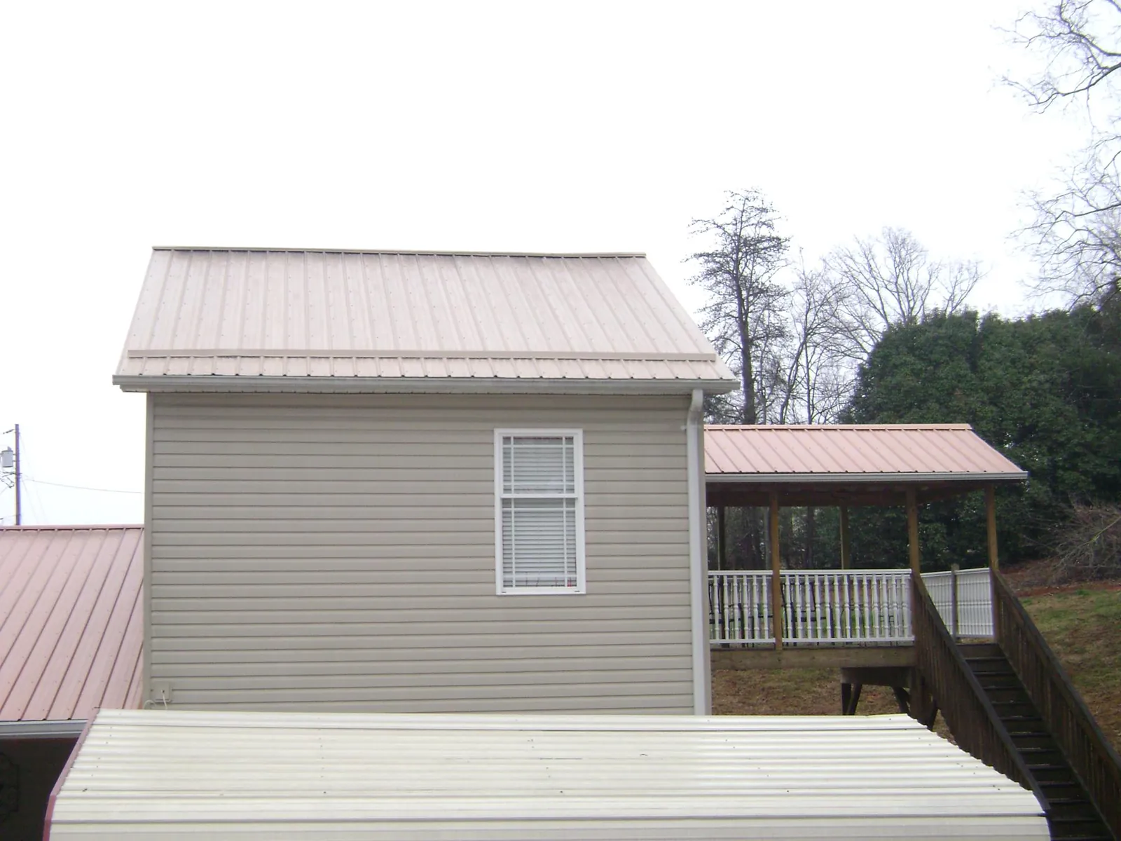 Tan metal roofs on a two story addition and attached porch, from a Roof Replacement job in New Zion