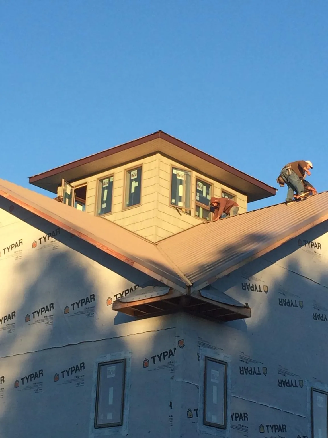 Roofers working around a rooftop cupola on a new metal roof at sunset — Roof Waterproofing in New Zion by Roofing Brothers